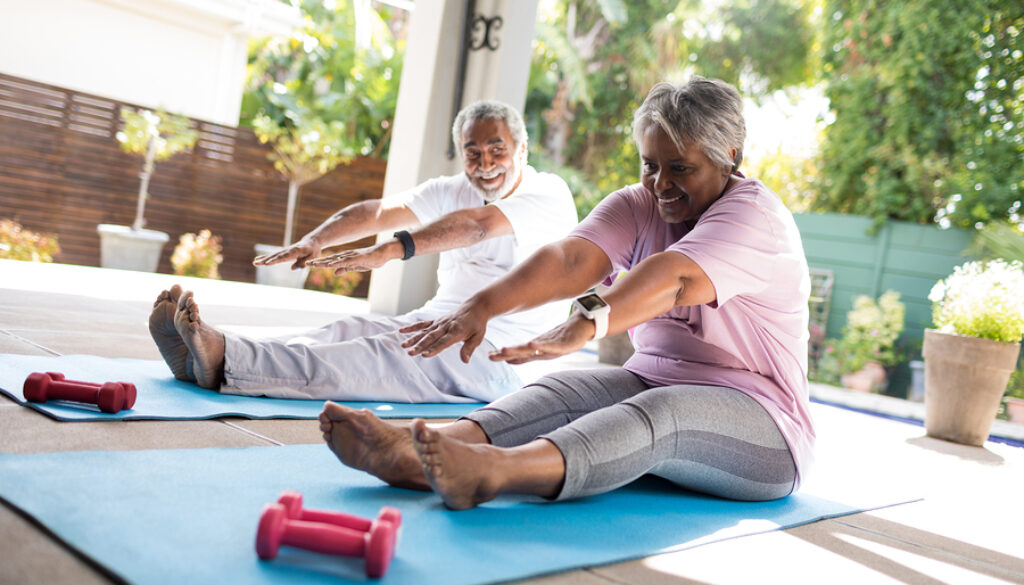 Full length of senior couple doing stretching exercise while sit