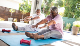 Full length of senior couple doing stretching exercise while sit