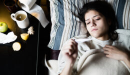 Sick young woman in bed at home having flu,measuring temperature