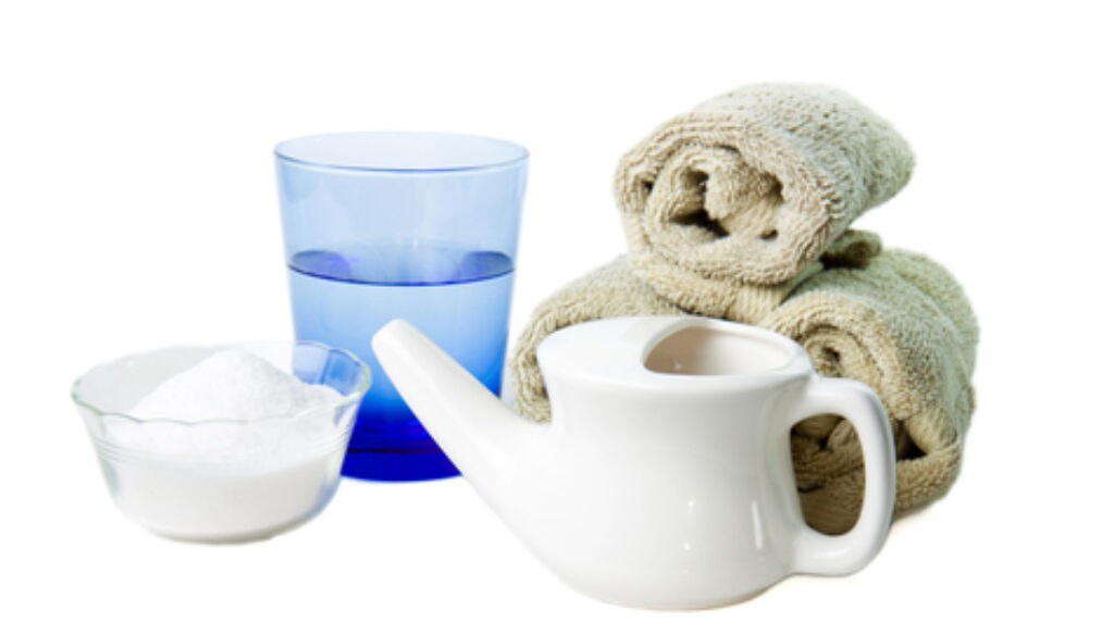Neti Pot with a glass of water and hand towels