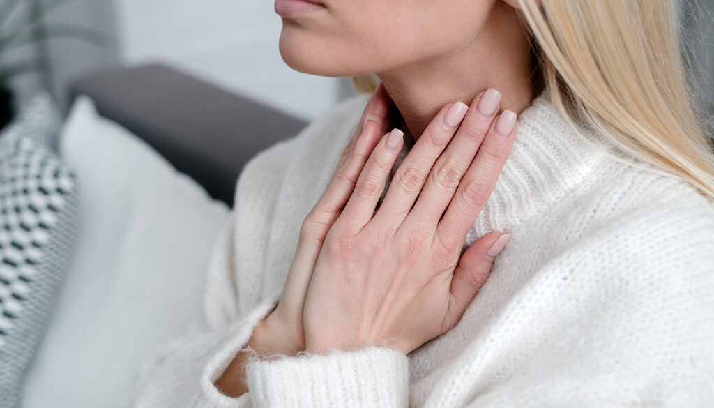 A Woman Rubs Her Throat for What Causes Thyroid Nodules