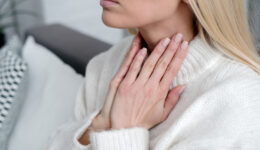 A Woman Rubs Her Throat for What Causes Thyroid Nodules