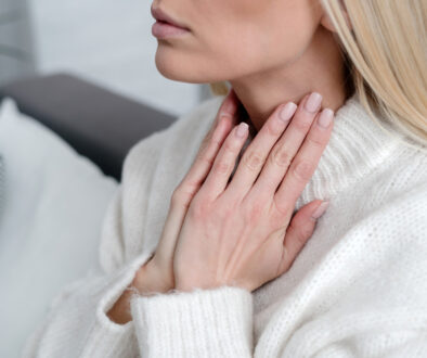 A Woman Rubs Her Throat for What Causes Thyroid Nodules