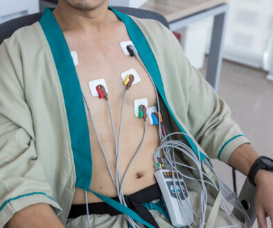 Man Sitting in a Chair Wearing a Holter Monitor Test